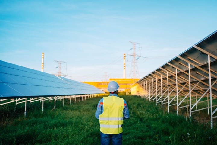 Engineer Surveys Solar Panels Under Clear Blue Sky