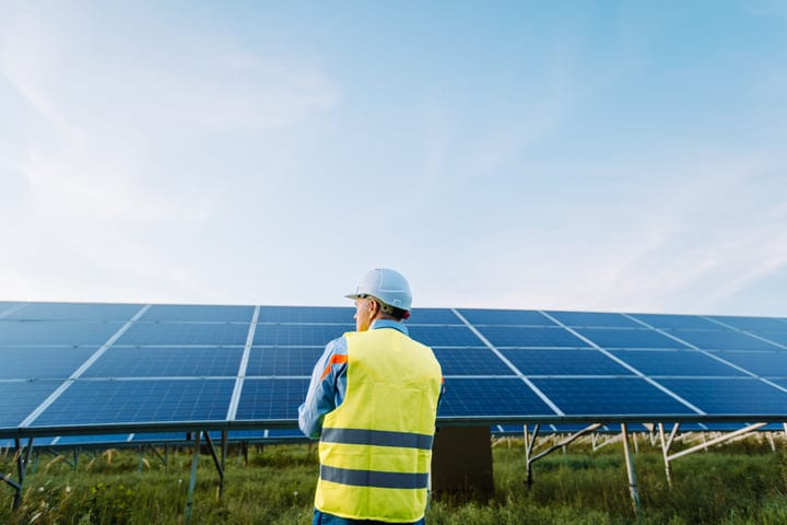 Engineer Surveys Solar Panels Under Clear Sky