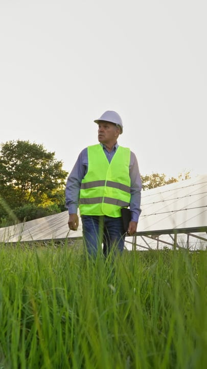 Solar Engineer Surveys Panels Amidst Lush Greenery