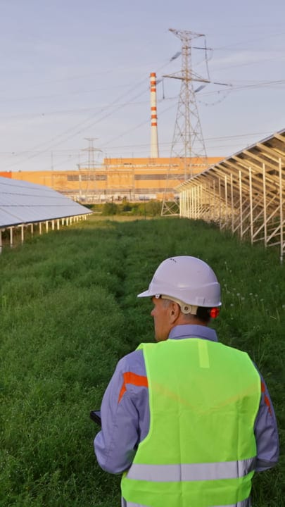 Engineer in High-Vis Vest Walking Through Solar Farm