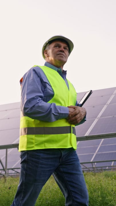 Focused Engineer Inspects Solar Panels Under Clear Skies