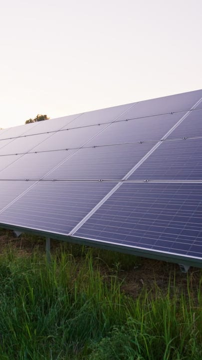 Sunset Glows Over A Field Of Solar Panels