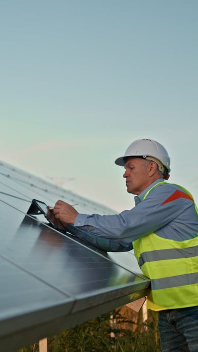 Engineer Checks Solar Panels Under Bright Blue Sky