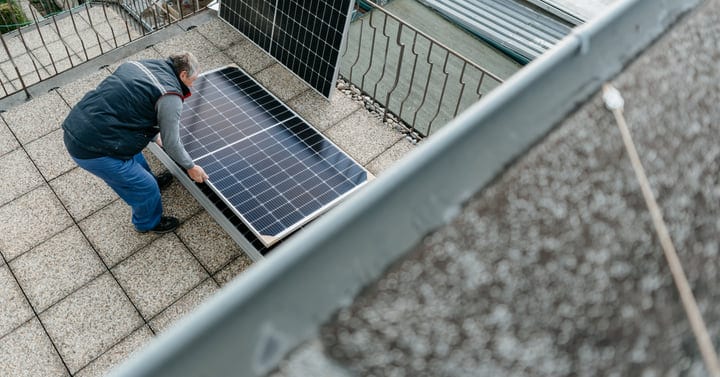 Solar Engineer Adjusts Panels On Urban Rooftop