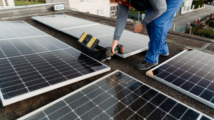 Technician Secures Solar Panels On Urban Rooftop