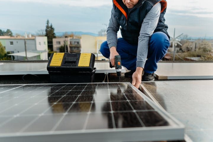 Focused Technician Secures Solar Panel On Rooftop Edge