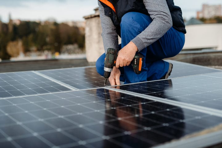 Focused Hands Secure Solar Panels On Rooftop