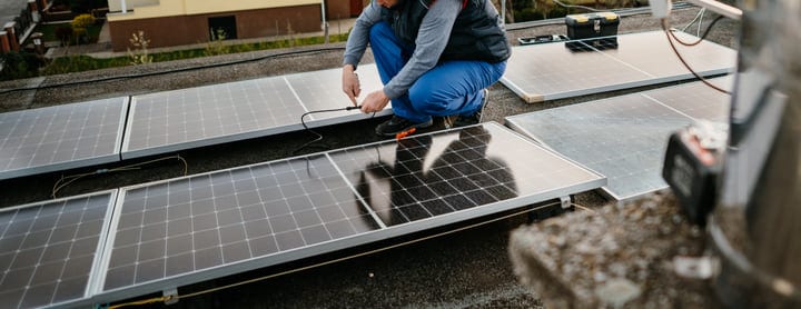 An Engineer Connects Solar Panels On A Rooftop