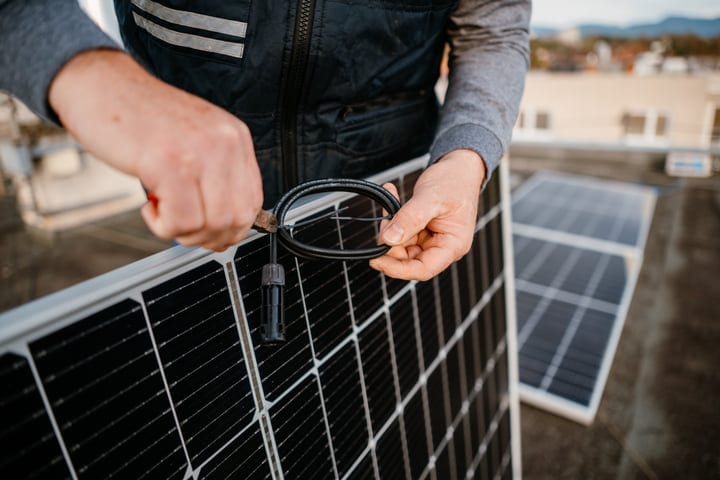Hands Skillfully Connect Wires On Solar Panel Rooftop