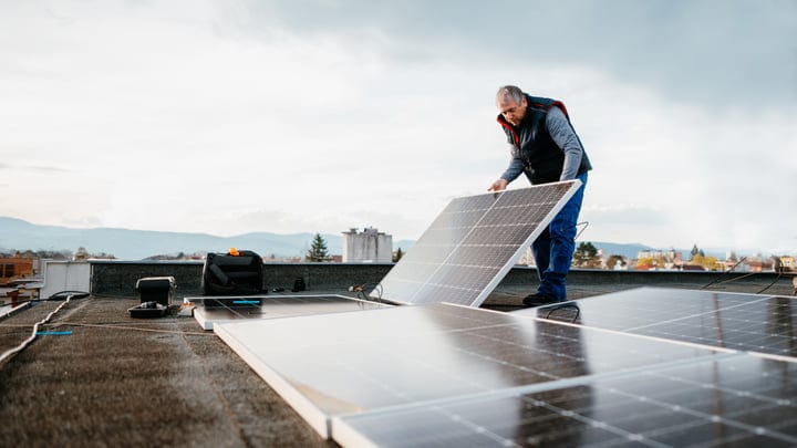 An Engineer Adjusts Solar Panels On A Rooftop