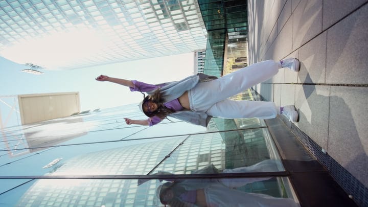 Joyful Dancer Leaps Against Urban Skyscraper Reflections