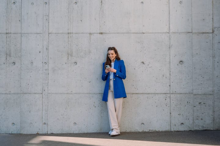 Young Woman Engages With Her Phone Against Urban Backdrop