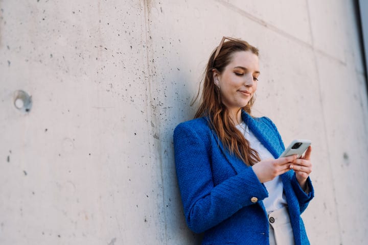 Young Woman Engages with Smartphone Against Urban Backdrop