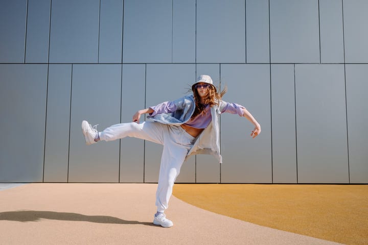 Dynamic Dancer Leaps Against Modern Urban Backdrop