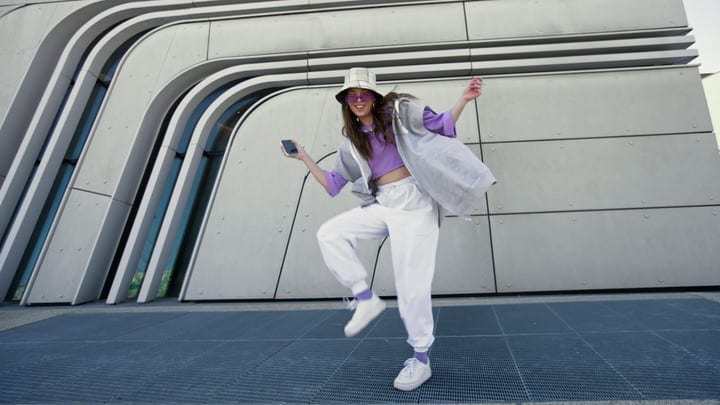 Joyful Street Dancer Moves Gracefully Against Urban Backdrop