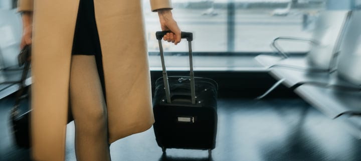 Traveler In Beige Coat Navigates Quiet Airport Terminal