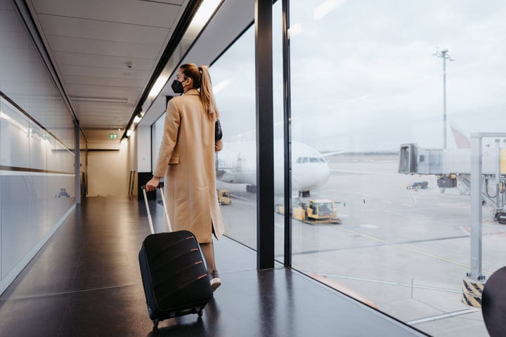 Traveler Navigates Airport Corridor With Rolling Luggage