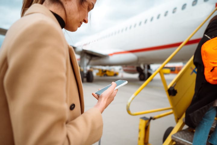 Traveler Checks Flight Details On Smartphone At Airport