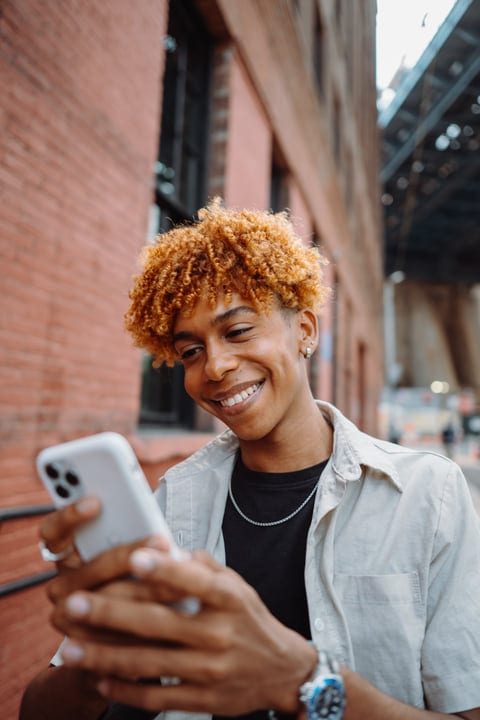 Smiling Youth Engages With Smartphone On Urban Street