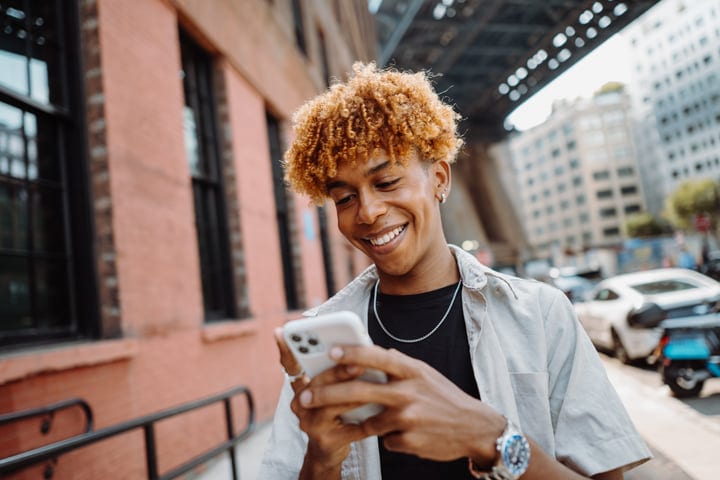 Young Person Engages With Smartphone In Vibrant Urban Scene