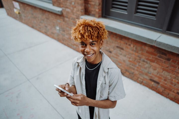 Joyful Youth Engages With Smartphone On City Street