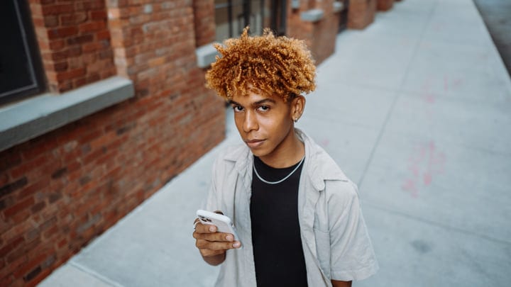 Young Man Engaged With Smartphone On Urban Street