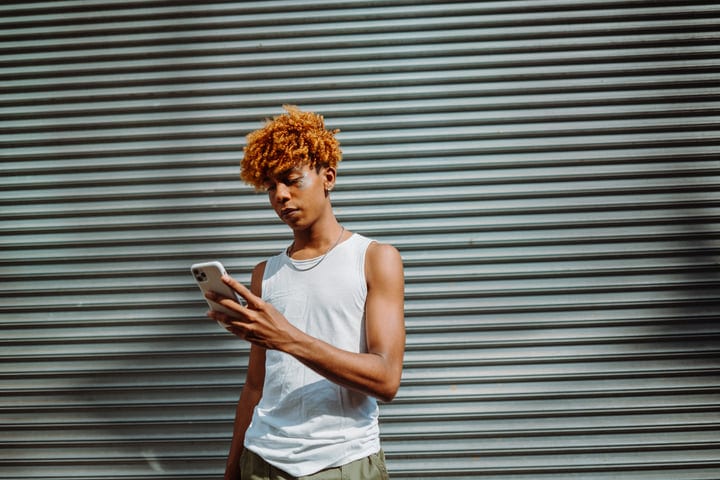 Young Urbanite Engages with Smartphone Against Metal Shutters