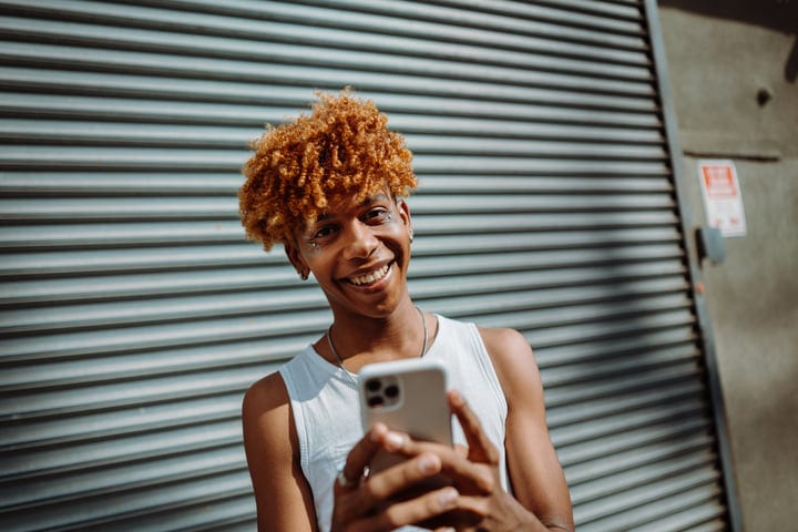 Smiling Youth Engaged With Smartphone On Urban Street