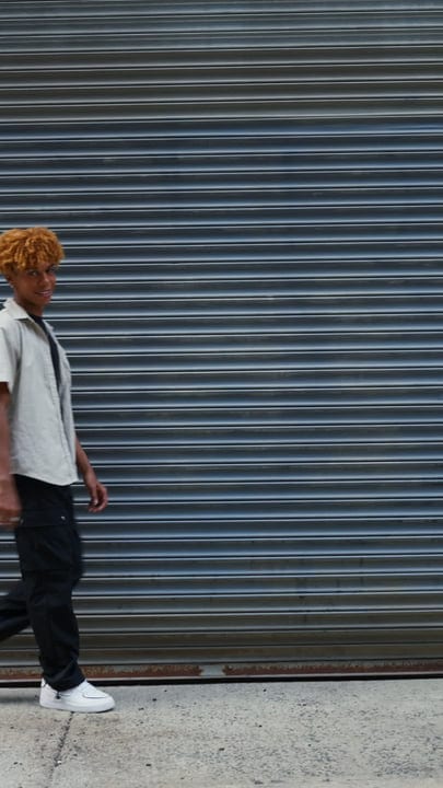 Confident Teen Strolls Past Urban Steel Shutters