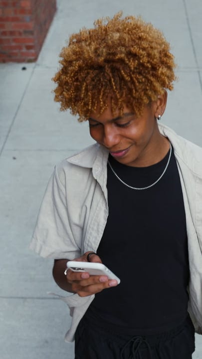 Young Person Engaged With Smartphone On City Sidewalk