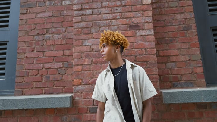 Contemplative Youth Leans Against a Brick Wall in NYC