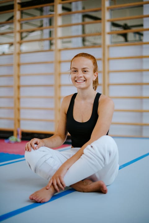 Smiling Woman Enjoys Parkour Training Indoors On Mat