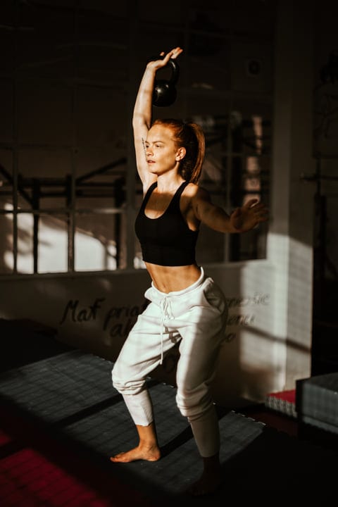 Empowered Woman Lifts Kettlebell Under Golden Light