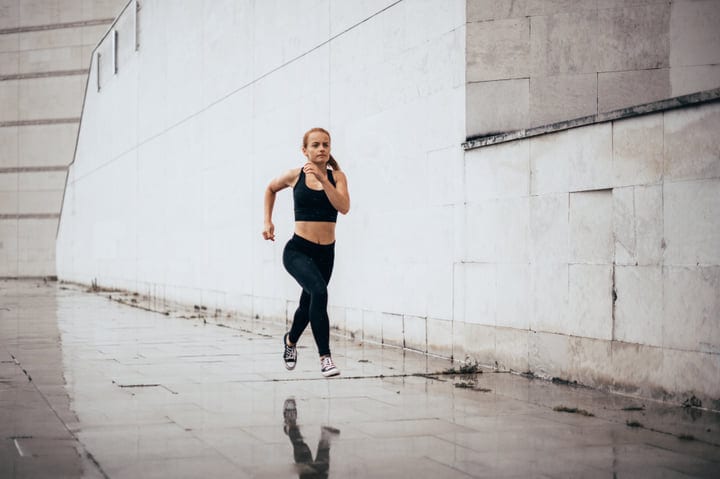 Dynamic Urban Parkour: Woman Sprinting on Wet Pavement