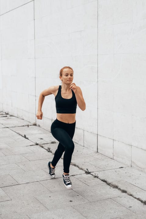 Determined Woman Running Along Urban Concrete Pathway