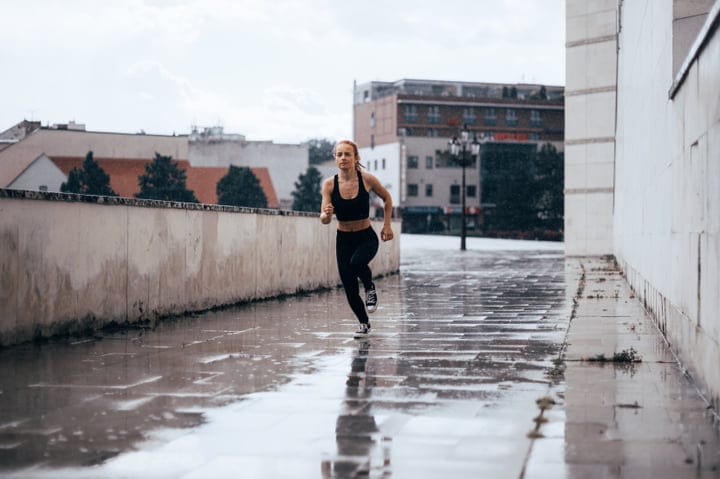 Determined Woman Running Through Rainy Urban Landscape