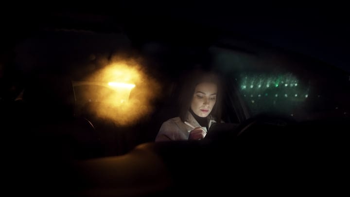 Focused Businesswoman Drives Through Mysterious Night Cityscape