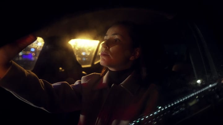 Businesswoman Adjusts Rearview Mirror During Night Drive