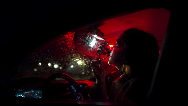 Businesswoman Applies Lipstick During Night Drive Home