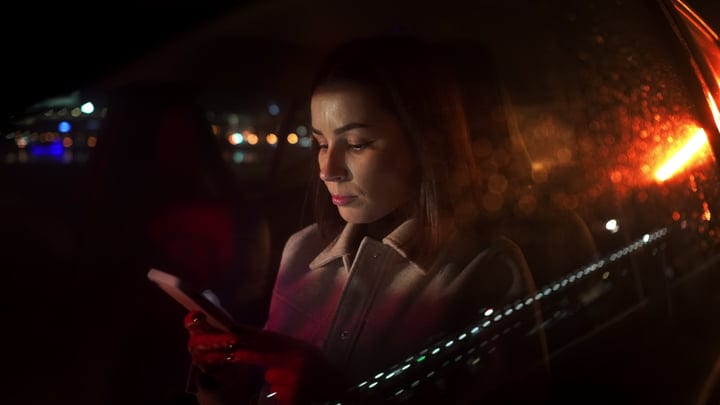 A Businesswoman Checking Her Phone During A Night Drive