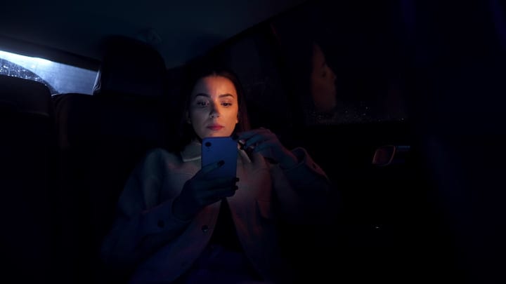 A Businesswoman Engages With Her Phone In Nightly Reflection