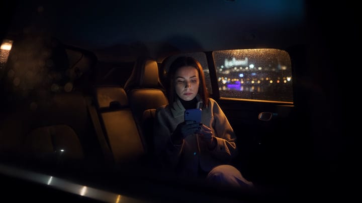 Focused Businesswoman Checks Her Phone During Night Drive