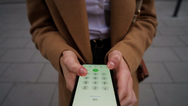 Businesswoman Dialing Number On Smartphone Screen Outdoors In Vienna Daytime
