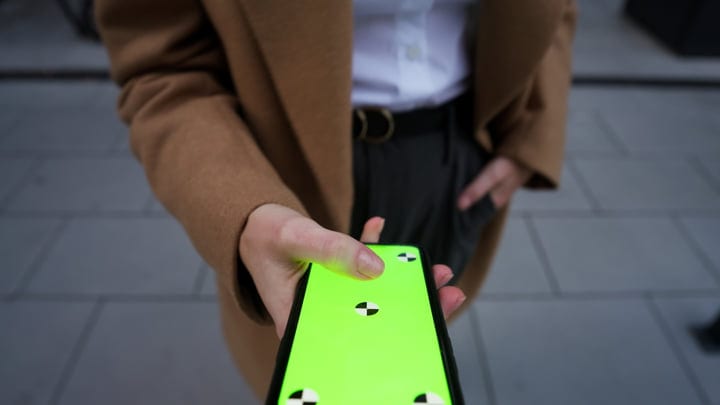 Woman in Camel Coat Holding Smartphone with Green Screen