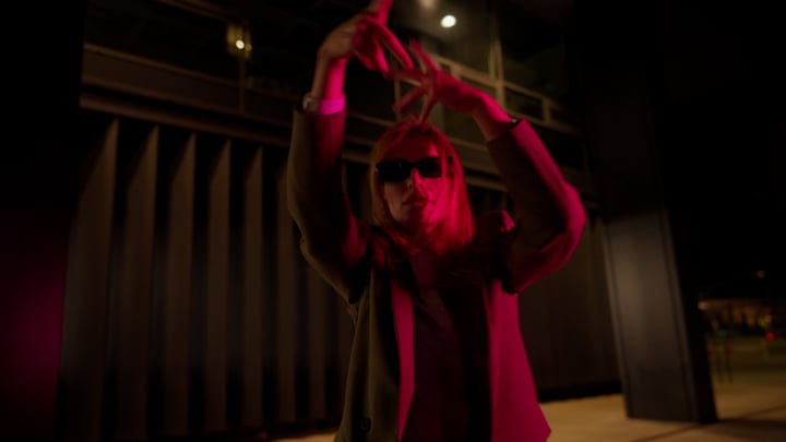 Woman In Sunglasses Hands Raised In Dramatic Pink Light