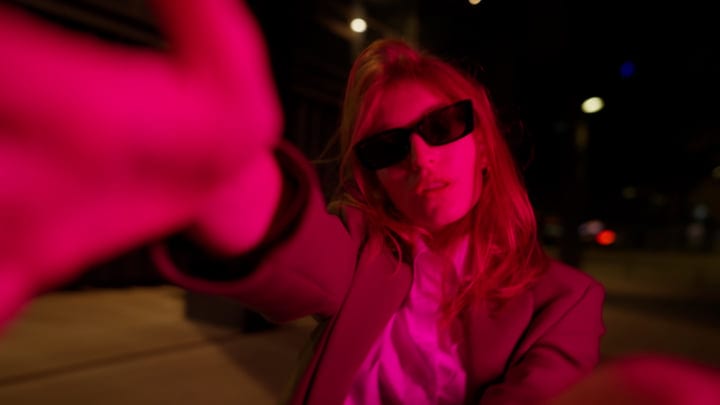 Woman In Sunglasses Capturing A Selfie In Vibrant Pink Urban Light