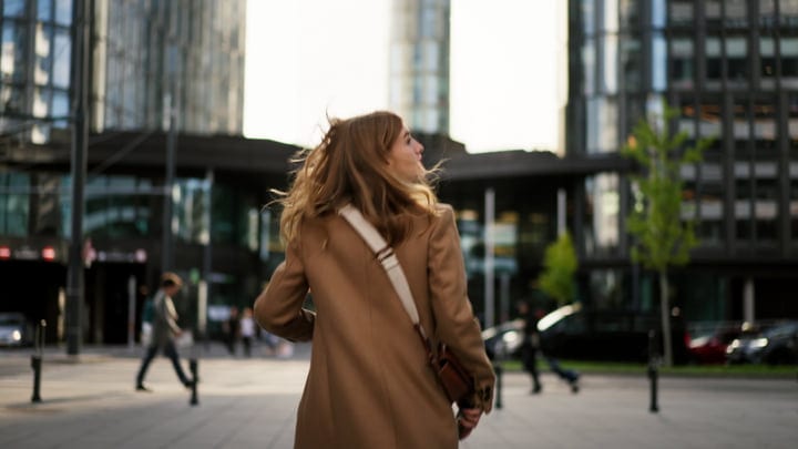 Businesswoman Walks Along Modern Street In Sunny Vienna Cityscape