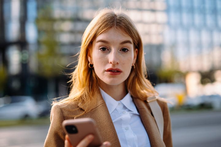 Contemplative Businesswoman Engages with Her Smartphone Outdoors