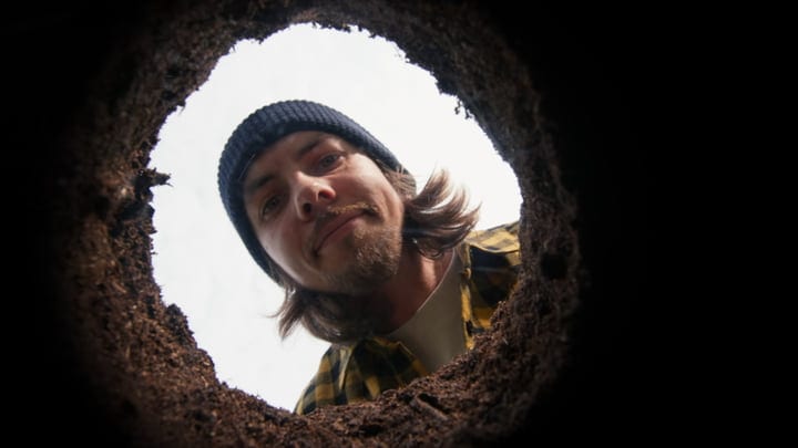 Gardener Peering Into A Freshly Dug Soil Hole