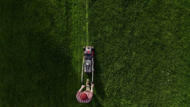 Bird's Eye View Of Gardener Mowing A Vibrant Lawn